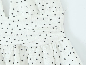 Détail du tissu en mousseline blanche à pois noirs avec une texture plissée à la taille