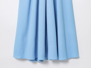 Detail of light blue pleated chiffon fabric showing vertical texture and draped hemline