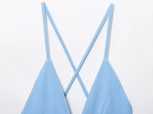 Detail of light blue dress with thin crisscross straps and textured fabric surface