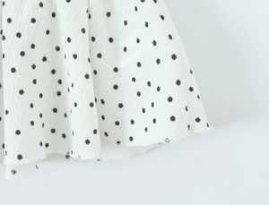 Gros plan sur tissu en mousseline blanche à pois noirs avec texture raffinée