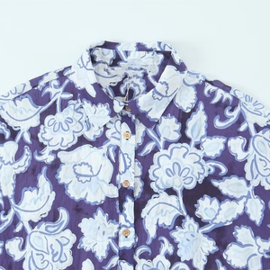 Dettaglio della camicia floreale con bottoni in legno e motivo di fiori azzurri