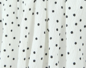 Vue détaillée du tissu en mousseline à pois blancs avec texture plissée et beau drapé