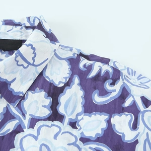 Dettaglio ravvicinato di una camicia a fiori con colletto a rever e motivi viola e blu