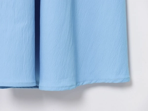 Detail shot of sky blue dress hem with delicate vertical crepe texture and flat stitching