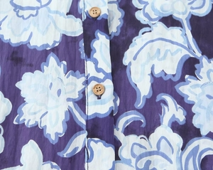 Dettaglio di camicetta a stampa floreale con bottoni tondi in legno e motivo a fiori viola
