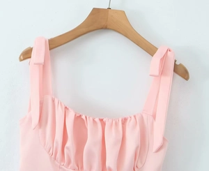 Detail of pink ruched neckline and bow shoulder straps on a sweet summer dress