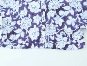 Dettaglio di camicia floreale con bottoni in legno su tessuto viola scuro di qualità