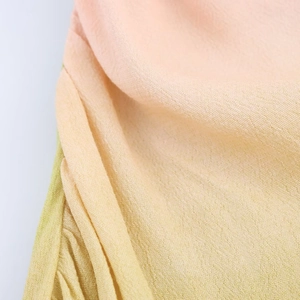Macro view of peach and green floral chiffon fabric with soft gradient pleats