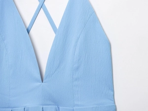 Detailed view of light blue deep V-neck dress with textured fabric and cross straps