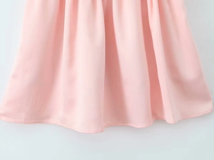Detail of light pink summer dress showing pleated hem texture and stitching quality