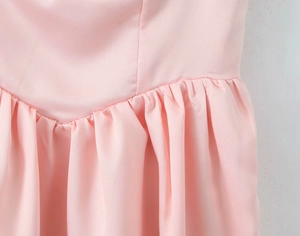 Detail shot of baby pink dress showing V-shaped waist seam and fine pleated fabric