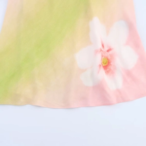 Close-up detail of light green chiffon dress with large white floral print and fine stitching