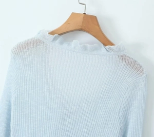 Close-up of light blue ribbed knit cardigan with delicate ruffled collar trim