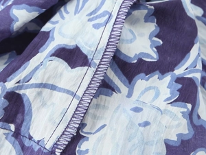Dettaglio ravvicinato della cucitura overlock su tessuto blu con stampa floreale