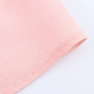 Macro shot of pink floral dress fabric texture and precision stitching on the hem