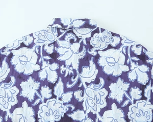 Dettaglio del colletto e della spalla di una camicia estiva viola con stampa floreale