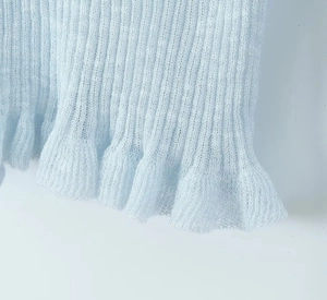Detailed view of light blue knit cardigan with soft lettuce edge hem and ribbed texture