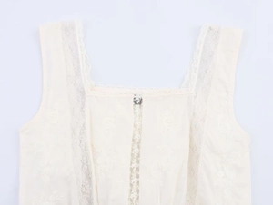 Close-up of cream sleeveless top with floral embroidery and delicate lace trim details