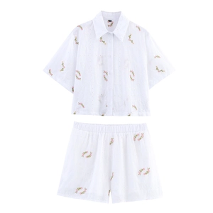Détail d'un ensemble blanc deux pièces avec broderie florale rose et détails ajourés