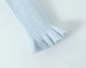 Detail of light blue knit cardigan cuff with delicate ruffle trim and ribbed texture