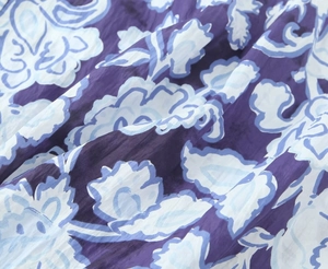 Dettaglio ravvicinato del tessuto viola leggero con motivo floreale blu e paisley