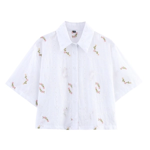 Détail de la chemise blanche brodée avec fleurs et étiquette de taille XS