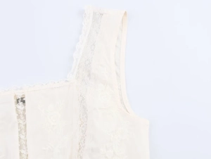 Detail of floral embroidery and layered lace trim on the cream square-neck top