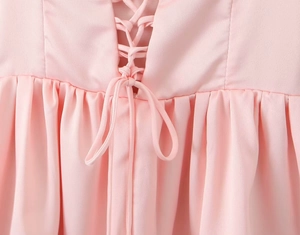 Close-up of pink summer dress featuring lace-up bodice and high-waisted pleated details
