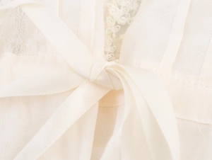 Detail of white lace trim and tie-up ribbon on breathable linen fabric for women