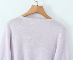 Close-up of light purple knitted cardigan featuring fine texture and ribbed neckline