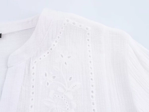 Dettaglio della camicia bianca in cotone con ricamo floreale traforato e scollo a V fine