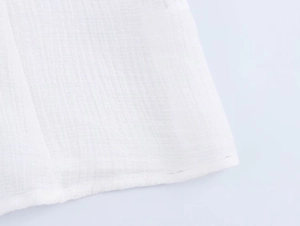 Dettaglio del ricamo traforato bianco su tessuto leggero in cotone e lino naturale