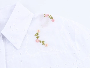 Détail de la chemise en coton blanc avec broderie anglaise florale et texture du col