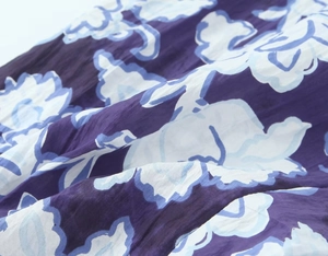 Vista dettagliata del tessuto viola scuro con stampa floreale blu chiaro e trama stropicciata
