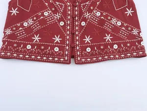 Détail du gilet rouge avec broderie géométrique blanche et sequins à effet miroir