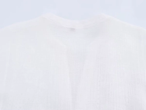 Dettaglio ravvicinato del colletto posteriore in cotone bianco con ricamo e trama naturale