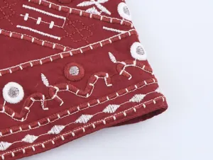 Détail de broderie ethnique sur jupe rouge foncé avec décoration effet miroir