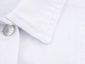 Nahaufnahme eines weißen Denim-Kragens mit geprägtem Metallknopf und Twill-Stoffstruktur