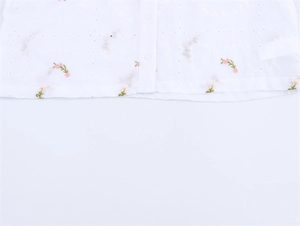 Détail de chemise blanche avec broderie florale délicate et motifs broderie anglaise