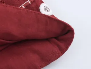 Détail du tissu en toile rouge foncé avec œillets brodés blancs et coutures précises