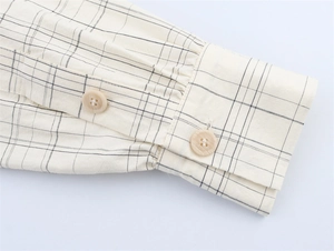 Detailed close-up of plaid shirt sleeve with dual wood texture buttons on fabric