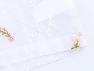 Gros plan d'une broderie florale blanche sur l'ensemble de chemise en coton de luxe