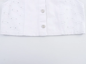 Detailaufnahme der weißen Jeansweste mit Ösenstickerei und silbernen Metallknöpfen