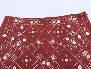Détail de broderie et fermeture éclair invisible sur la taille d'une jupe rouge