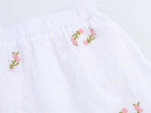 Détail du short blanc en broderie anglaise avec fleurs roses et taille élastique