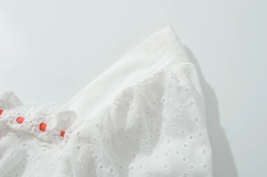 Détail macro de dentelle de coton blanche avec broderie florale et ruban orange