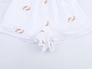 Détail du short blanc en broderie anglaise avec fleurs roses et taille élastique
