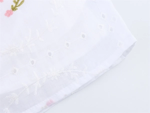 Détail du tissu en coton blanc avec broderie florale et motifs de vigne ajourés