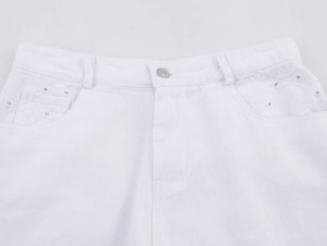 Detail der weißen Denim-Shorts mit aufwändiger Ösenstickerei und Knopfverschluss