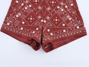 Vue détaillée des broderies géométriques blanches sur une jupe rouge foncé pour femme